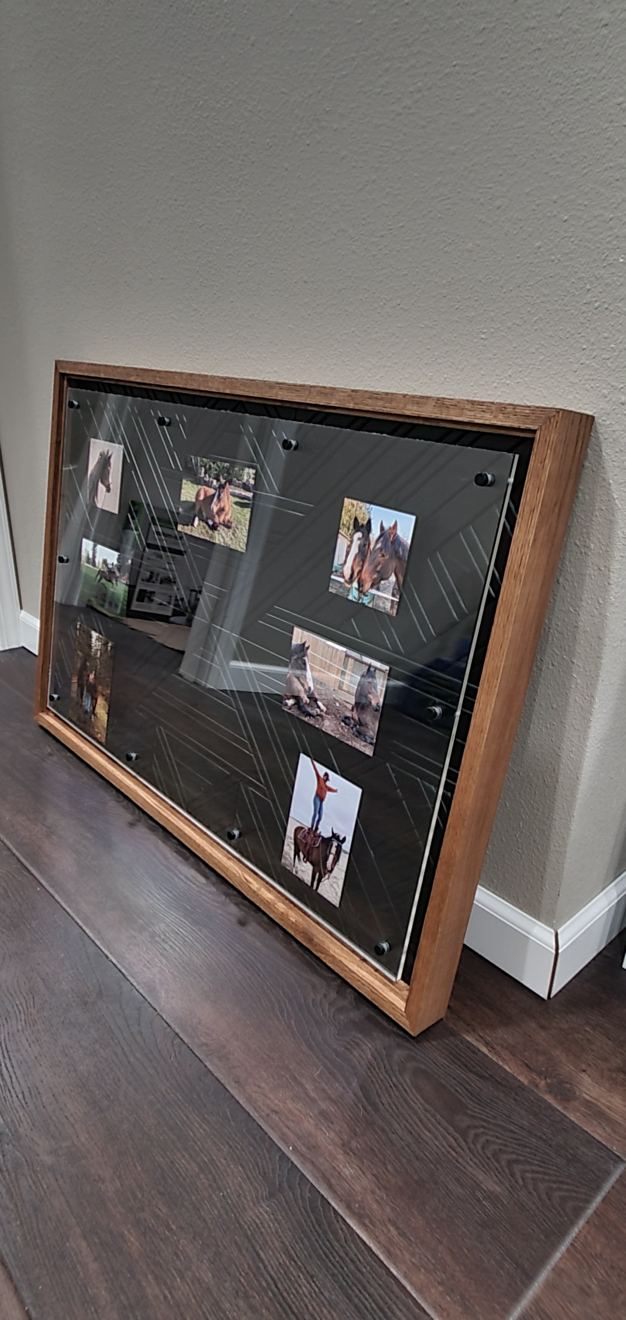 Wooden picture frame with photos inside, mounted on a wall.